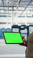 Vertical Server room admin uses isolated screen tablet to increase supercomputers workload capacity. Data center worker configures gear with chroma key device notebook, improving processing speed, camera A video