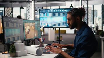 mitten östra ingenjör slutföra interiör design planer för en byggnad i kontor, arbetssätt mot bostads- projekt layout och strukturera på dubbel monitorer dator. stad planera. kamera a. video