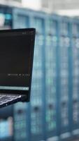 Vertical Data center engineer doing AI data analysis on laptop to upgrade infrastructure. Server room worker using notebook to manage storage systems for machine learning training datasets video