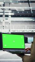 Vertical Engineer at work using green screen laptop in data center to check hardware for system stability. Worker using mockup notebook to oversee server farm and configure infrastructure, camera A video