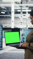 vertikal administration i data Centrum använder sig av app på grön skärm bärbar dator till säkerställa fel fri stordatorer nätverk. den specialist användningar attrapp anteckningsbok till övervaka server nav redskap delar för misslyckanden, kamera en video