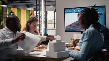 equipo miembros trabajo juntos en oficina con arquitectónico software y 3d modelos a Visualizar un exitoso residencial propiedad con inteligente ciudad infraestructura objetivos. urbano desarrollo. cámara una. video