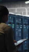 Vertical Developer doing data center automation using AI neural networks on tablet. Server room IT professional implements deep learning driven predictive maintenance systems using device, camera B video