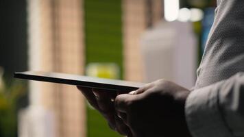 African american developer evaluating 3D models blueprints and digital software as part of strategic housing project in urban development area. City planning business project on tablet. Camera B. video