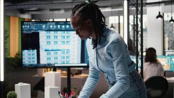 Real estate staff member evaluating architectural measurements on blueprints and 3D models for the construction project. Developer with a new residential project for the future. Camera A. video