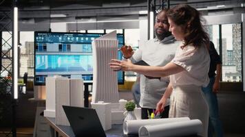 Property developers discuss the challenges of city planning and land acquisition, using 3D models to visualize residential layout expansion and infrastructure upgrades on the table. Camera A. video