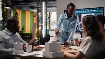 multiétnico arquitectura desarrolladores utilizando 3d modelos en lluvia de ideas reunión, muestra arquitectónico software a trabajo en estructural ciudad planificación. residencial proyecto para urbano desarrollo. cámara una. video