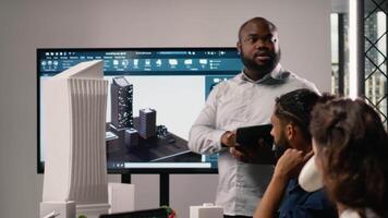Urban development diverse team discussing property investment new strategy for project approval in a bright office setting, analyzing blueprints and 3D models on architectural software. Camera B. video