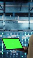 Vertical Data center software developer uses green screen tablet to minimize infrastructure downtime. IT specialist in server hub enhancing data protection safeguards using mockup device, camera A video
