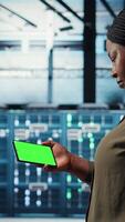 Vertical Server hub admin uses isolated screen smartphone to watch tutorial on how to increase rigs workload capacity. Data center worker following guide on chroma key phone to improve speed, camera A video