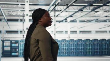 manager wandelen in gegevens centrum, toezicht houden op groot schaal het hardware naar in stand houden naadloos activiteiten. server kamer arbeider aan het doen netwerk beheer voor is gestegen beschikbaarheid, camera b video