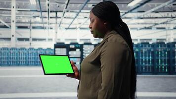 Server room admin uses isolated screen tablet to increase supercomputers workload capacity. Data center worker configures gear with chroma key device notebook, improving processing speed, camera A video