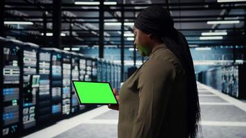 Daten Center Programmierer Verwendet Grün Bildschirm Tablette zu sich entwickeln Katastrophe Wiederherstellung Pläne, Minimieren Ausfallzeit. es Experte im Server Bauernhof, verbessern Daten Schutz Protokolle mit Chroma Schlüssel Gerät, Kamera ein video