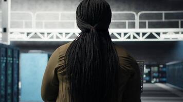 Engineer in server hub using laptop to upgrade rigs for increase in workload capacity using AI deep learning. Data center employee uses artificial intelligence to improve processing speed, camera B video