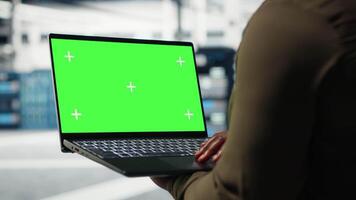 Technician with green screen laptop in data center implementing advanced power management solutions. Employee using mockup notebook to oversee server hub, reducing energy consumption, camera B video