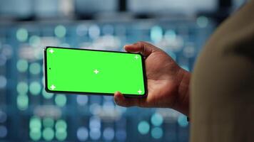 Server hub admin uses isolated screen smartphone to watch tutorial on how to increase rigs workload capacity. Data center worker following guide on chroma key phone to improve speed, camera B video