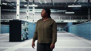 beheerder wandelen in gegevens centrum, toezicht houden op groot schaal het infrastructuur naar in stand houden naadloos activiteiten. server boerderij werknemer aan het doen netwerk beheer voor is gestegen beschikbaarheid, camera een video