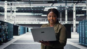 Programmierer im Daten Center mit Laptop zu Aktualisierung Systeme zum ist gestiegen Stabilität. es Fachmann im Server Bauernhof konfigurieren Infrastruktur mit Notizbuch zum Optimum Leistung, Kamera ein video