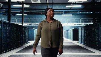 porträtt av glad data Centrum ingenjör övervaka den Utrustning till upprätthålla sömlös operationer. glad den specialist gående i server rum, håller på med nätverk förvaltning för ökade upptid, kamera en video