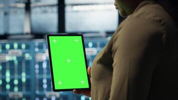 Administrator mit isoliert Bildschirm Tablette im Daten Center Umsetzung fortgeschritten Leistung Verwaltung Lösungen. Mitarbeiter mit Chroma Schlüssel Gerät zu überwachen Server Hub, reduzieren Energie Verbrauch, Kamera b video