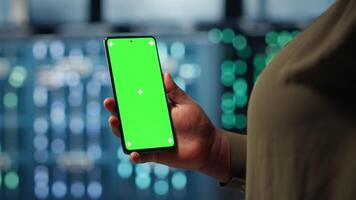 Manager using app on chroma key phone to check server farm energy consumption. Data center system administrator using application on green screen smartphone to check power usage levels, camera B video