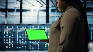 vicino su di tecnico a opera utilizzando verde schermo tavoletta nel dati centro per dai un'occhiata hardware per sistema stabilità. dipendente utilizzando modello dispositivo per sorvegliare server azienda agricola e configure attrezzatura, telecamera un' video