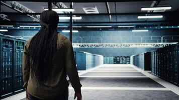 data Centrum chef utför säkerhet revisioner till skydda mot cyber hot och fel. anställd gående mellan server rum rader, säkerställa överensstämmelse med industri standarder, kamera en video