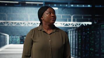 porträtt av glad data Centrum ingenjör övervaka den Utrustning till upprätthålla sömlös operationer. glad den specialist gående i server rum, håller på med nätverk förvaltning för ökade upptid, kamera b video