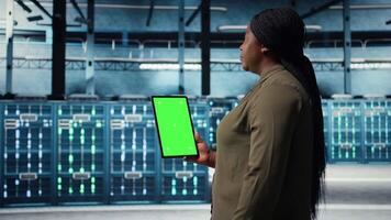 Administrator mit isoliert Bildschirm Tablette im Daten Center Umsetzung fortgeschritten Leistung Verwaltung Lösungen. Mitarbeiter mit Chroma Schlüssel Gerät zu überwachen Server Hub, reduzieren Energie Verbrauch, Kamera ein video