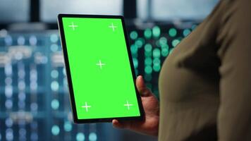 programvara utvecklare på arbete använder sig av grön skärm läsplatta i data Centrum till kolla upp hårdvara för systemet stabilitet. afrikansk amerikan kvinna använder sig av krom nyckel enhet till övervaka server odla, kamera b video