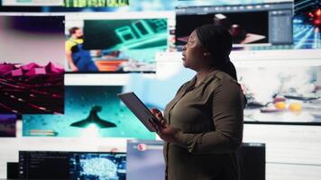 stänga upp av person använder sig av läsplatta, njuter fritid tid med uppkopplad innehåll. kvinna bläddring social media app på enhet i främre av digital bakgrund fylld med clips collage layout, kamera en video