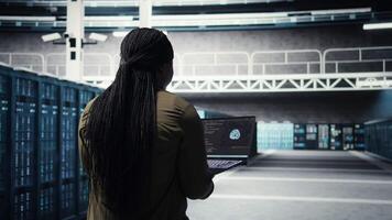 Engineer in server hub using laptop to upgrade rigs for increase in workload capacity using AI deep learning. Data center employee uses artificial intelligence to improve processing speed, camera A video