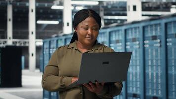 Programmierer im Daten Center mit Laptop zu Aktualisierung Systeme zum ist gestiegen Stabilität. es Fachmann im Server Bauernhof konfigurieren Infrastruktur mit Notizbuch zum Optimum Leistung, Kamera b video