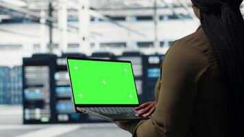 computadora científico a trabajo utilizando verde pantalla ordenador portátil en datos centrar a cheque hardware para sistema estabilidad. gerente utilizando Bosquejo cuaderno a supervisar servidor granja engranaje, cámara si video