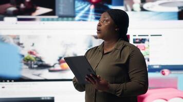 stänga upp av person använder sig av läsplatta, njuter fritid tid med uppkopplad innehåll. kvinna bläddring social media app på enhet i främre av digital bakgrund fylld med clips collage layout, kamera b video