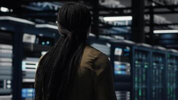 data Centrum chef utför säkerhet revisioner till skydda mot cyber hot och fel. anställd gående mellan server rum rader, säkerställa överensstämmelse med industri standarder, kamera b video