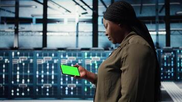 Server hub admin uses isolated screen smartphone to watch tutorial on how to increase rigs workload capacity. Data center worker following guide on chroma key phone to improve speed, camera A video