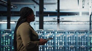 datos centrar técnico monitores datos centrar métrica en tableta a mejorar equipo Operacional eficacia. empleado camina en servidor centro, utilizando analítica en dispositivo a predecir actuación, cámara si video