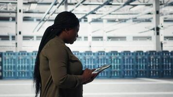 tecnico a piedi nel dati centro con tavoletta, controllo hardware per sistema stabilità. lavoratore supervisione server azienda agricola con dispositivo, configurazione infrastruttura impianti di perforazione, telecamera B video