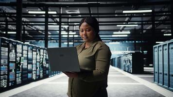 técnico utilizando ordenador portátil en alto tecnología datos centro, integrando nuevo tecnologías y sistemas eso experto utilizando cuaderno a supervisar servidor granja plataformas, asegurando conformidad con industria estándares, cámara un video