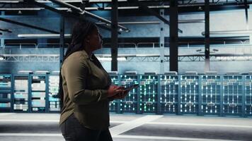 datos centrar técnico monitores datos centrar métrica en tableta a mejorar equipo Operacional eficacia. empleado camina en servidor centro, utilizando analítica en dispositivo a predecir actuación, cámara un video