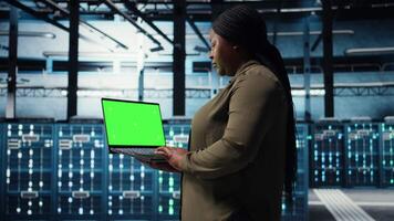 dati centro Admin usi isolato schermo il computer portatile per sviluppare disastro recupero piani, minimizzando tempi di inattività. donna nel server azienda agricola valorizzare dati protezione protocolli utilizzando modello taccuino, telecamera un' video