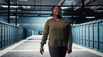 handledare i data Centrum övervaka stor skala den Utrustning till upprätthålla sömlös operationer. den expert- gående mellan server rum rader, håller på med nätverk förvaltning för ökade upptid, kamera en video