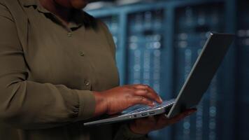 Close up of manager working in data center using laptop to optimize network infrastructure. IT worker in server farm diagnosing and resolving hardware malfunctions using notebook video