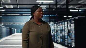 software desarrollador caminando en datos centro, comprobación hardware para sistema estabilidad. sistema administrador supervisando servidor granja habitación, supervisión infraestructura plataformas, cámara si video