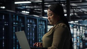 técnico utilizando ordenador portátil en alto tecnología datos centro, integrando nuevo tecnologías y sistemas eso experto utilizando cuaderno a supervisar servidor granja plataformas, asegurando conformidad con industria estándares, cámara si video