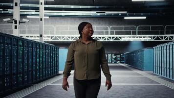 porträtt av leende administration gående i data Centrum, övervaka stor skala den infrastruktur till upprätthålla sömlös operationer. Lycklig server bruka anställd nöjd förbi ökade upptid, kamera en video