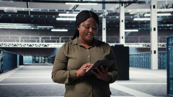 datos centrar programador monitores datos centrar métrica en tableta a mejorar engranaje Operacional eficacia. africano americano empleado en servidor cubo utilizando analítica a predecir actuación, cámara un video