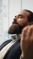 vertical CEO inclina-se costas dentro dele escritório cadeira noivando dentro uma guiado meditação sessão com branco barulho, usando uma meditação aplicativo. comprometimento para atenção para carreira sucesso e mental clareza. Câmera uma. video