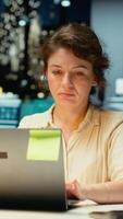 Vertical Female employee proofreading a document before transcribing on notebook, handwritten notes on paper after hours. Woman engaged in documenting important ideas from archived report. Camera B. video